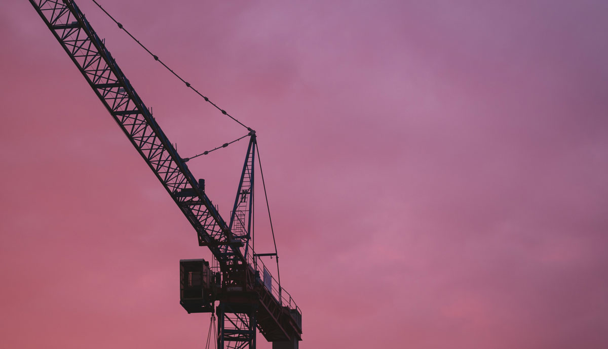 Silhouette of a crane against a purple sunset sky