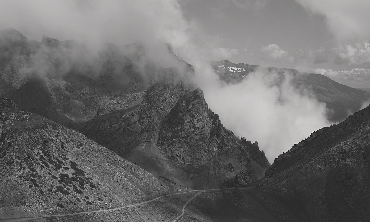 Black and white valley with clouds contrasting against the mountains